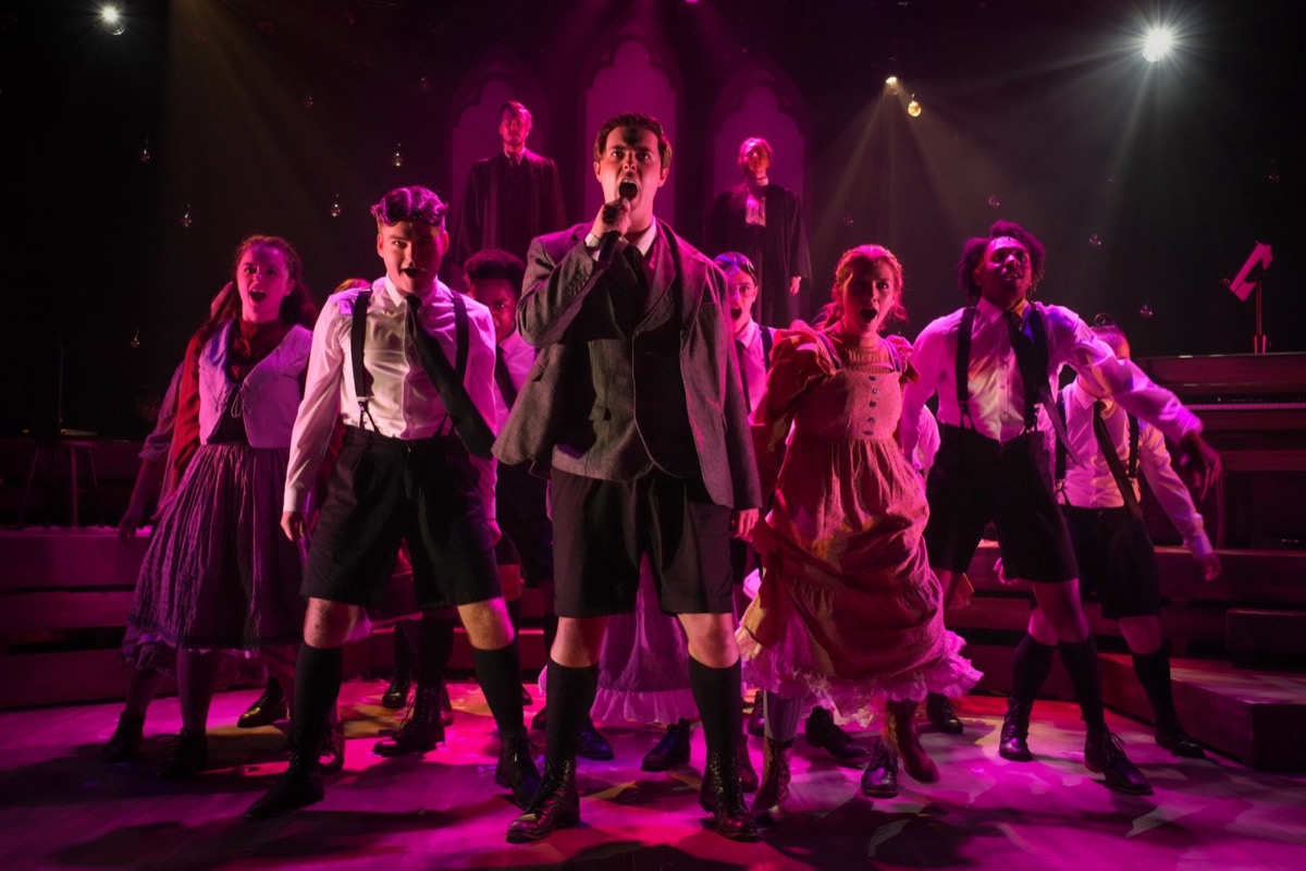 AMDA musical theatre students performing an ensemble number under magenta stage light